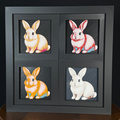 Four-panel framed geometric rabbit layered art set showing the same sitting rabbit design in four WTX3D color palettes, arranged in a charcoal black 2x2 frame with tall ears, soft fur detail, and high-contrast layered color.