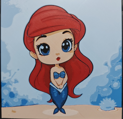 Framed 3D layered art piece featuring an adorable chibi illustration of a mermaid princess character with long flowing bright red hair, a blue seashell top, and a matching blue tail, standing on a sandy floor against a soft blue ocean background.