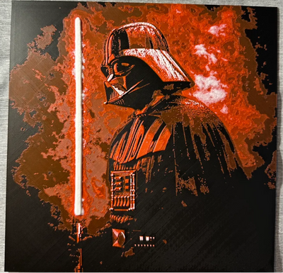 Framed 3D layered art piece featuring a dramatic, high-contrast stylized illustration of an iconic sci-fi dark villain character in a black helmet and cape, shown in profile. The character is holding a glowing vertical red lightsaber blade on the left. The background features an intense, highly textured aura of explosive red and orange smoke against a solid black backdrop.