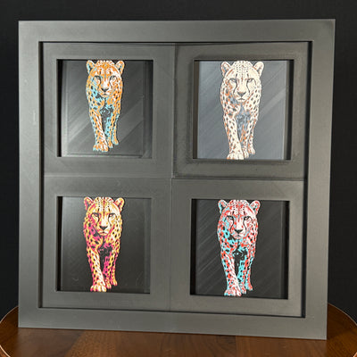 Four-panel framed geometric cheetah layered art set showing the same walking cheetah design in four WTX3D color palettes, arranged in a charcoal black 2x2 frame with spotted fur detail, sleek body shape, and high-contrast layered color.
