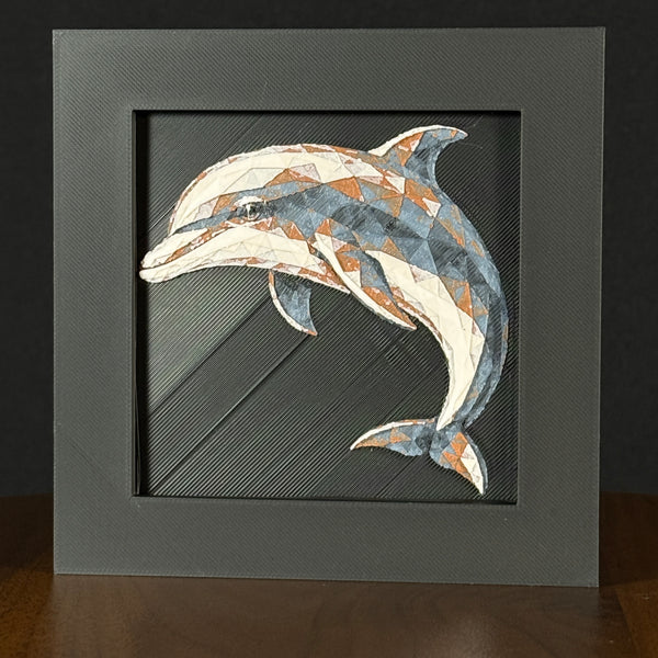 Geometric dolphin framed layered 3D art in Heritage color palette, featuring a leaping dolphin with soft white, gray, black, and neutral brown layered details inside a charcoal matte display frame.