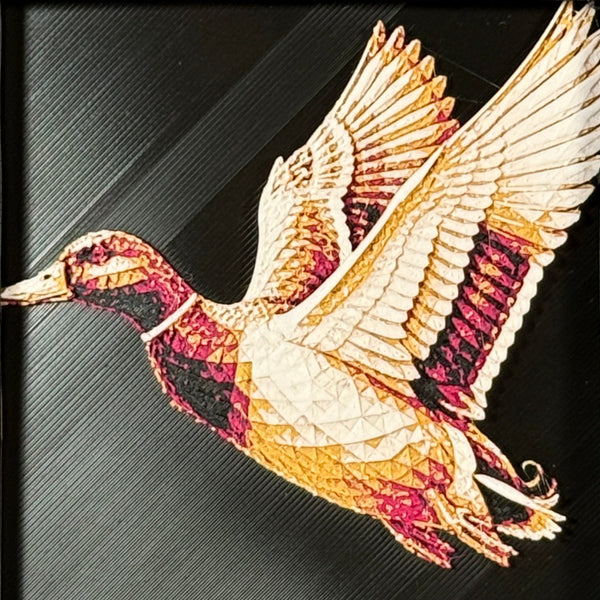 Geometric duck framed layered 3D art in Royal Gold color palette, featuring a flying duck with gold, blue, black, and white layered details inside a charcoal matte display frame.