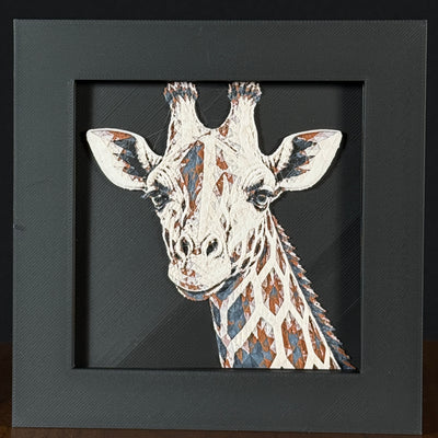 Geometric giraffe framed layered 3D art in Heritage color palette, featuring a bold giraffe portrait with soft white, gray, black, and neutral brown layered details inside a charcoal matte display frame.