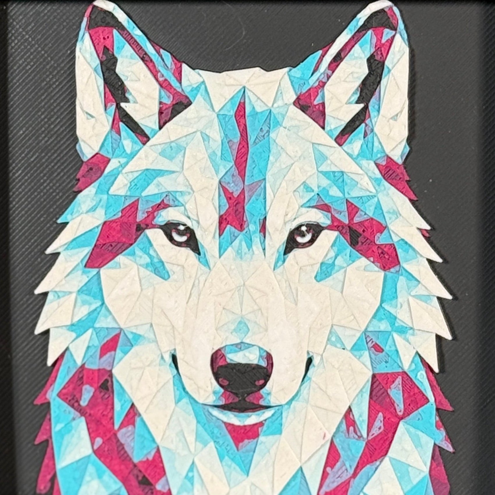Geometric wolf framed layered 3D art in Crimson Ice color palette, featuring a bold wolf portrait with cyan, red, magenta, black, and white layered details inside a charcoal matte display frame.