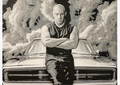 Framed 3D layered art piece featuring a stylized monochrome illustration of a bald action movie hero standing with crossed arms while leaning against the front of a classic muscle car. The background shows dramatic, high-contrast clouds of smoke and textured patterns in a grayscale color scheme.