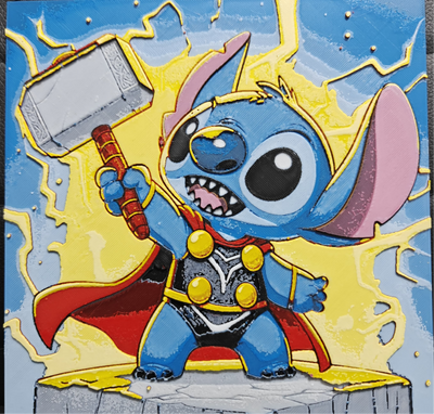 Framed 3D layered art piece featuring a dynamic and heroic illustration of a cute blue alien character dressed as a comic book thunder god, wearing a golden headpiece, a black and silver armor suit with a flowing red cape, and triumphantly hoisting a large silver war hammer into the air amidst crackling yellow lightning bolts against a blue sky background.