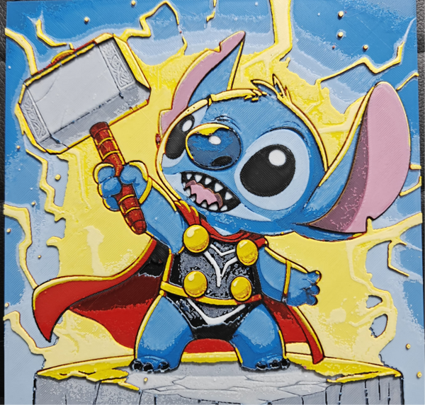 Framed 3D layered art piece featuring a dynamic and heroic illustration of a cute blue alien character dressed as a comic book thunder god, wearing a golden headpiece, a black and silver armor suit with a flowing red cape, and triumphantly hoisting a large silver war hammer into the air amidst crackling yellow lightning bolts against a blue sky background.