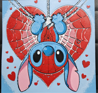 Framed 3D layered art piece featuring an adorable illustration of a cute blue alien character dressed in a red, web-patterned comic hero mask and torso, hanging upside down from a silver thread in front of a large red heart with web details, surrounded by smaller red hearts against a light blue background.