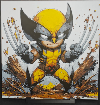 Framed 3D layered art piece featuring an intense chibi illustration of a fierce comic book mutant hero wearing a classic yellow and dark grey suit with a pointed mask, aggressively posing with three metal claws extended from each fist amidst rocky ground and debris against a light background.