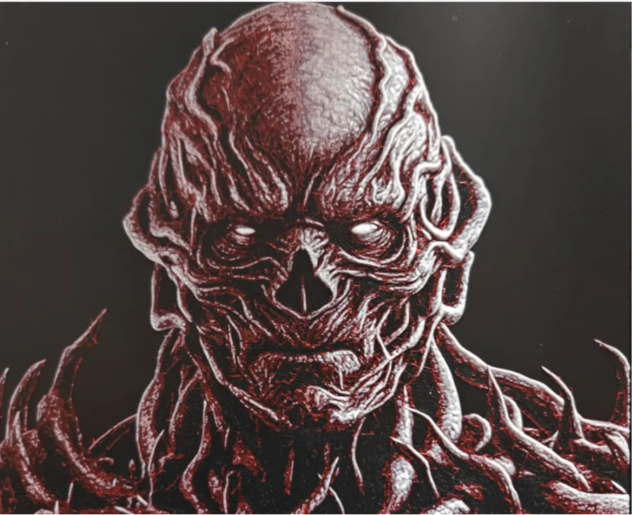 Framed 3D layered art piece featuring a detailed portrait of a sinister, fleshy sci-fi humanoid monster with exposed muscular tendrils and vines covering its body against a dark background.