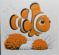 Framed 3D layered art piece featuring a stylized, friendly orange and white clownfish swimming next to textured orange sea anemones on a light background.