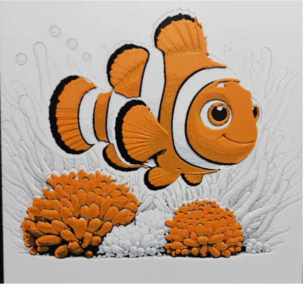 Framed 3D layered art piece featuring a stylized, friendly orange and white clownfish swimming next to textured orange sea anemones on a light background.