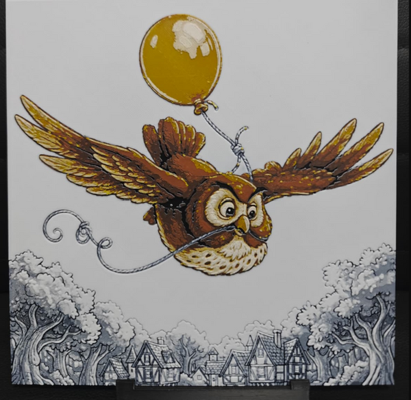 Framed 3D layered art piece featuring a charming illustration of a brown owl with outstretched wings flying while holding the string of a glossy yellow balloon in its beak. Below the owl is a detailed monochromatic, black-and-white sketch of a fairy tale village with vintage houses and lush trees.