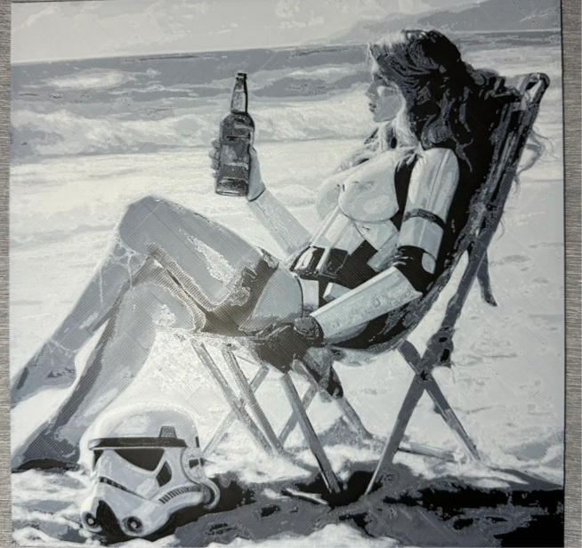 Framed 3D layered art piece featuring a humorous monochrome grayscale illustration of a woman wearing sci-fi trooper-inspired armor elements and a bikini, relaxing on a folding lawn chair at the beach while holding up a glass bottle. An iconic sci-fi soldier helmet rests on the sand next to her chair against a background of crashing ocean waves.