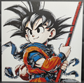Framed 3D layered art piece featuring a detailed illustration of a young anime warrior character with spiky black hair, wearing a classic orange and blue martial arts uniform while holding a red staff over his shoulder.
