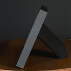 Side view of a WTx3D charcoal matte frame with the built-in easel stand open on a wooden surface.
